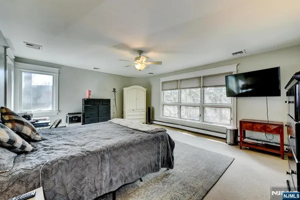 a spacious bedroom with a bed a window and a flat screen television