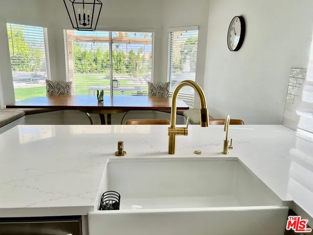 a dining hall with stainless steel appliances granite countertop a stove a refrigerator a kitchen island a couches and chairs with wooden floor