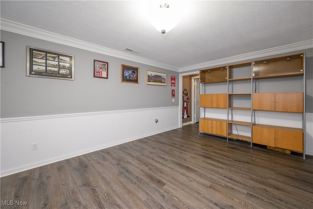 2061 Portage Line Road Mogadore, OH 44260 - Photo 39 of 48 Empty room featuring dark wood finished floors, crown molding, a textured ceiling, and wainscoting