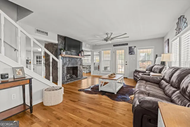 a kitchen with stainless steel appliances kitchen island granite countertop a refrigerator a stove top oven a sink dishwasher and white cabinets with wooden floor