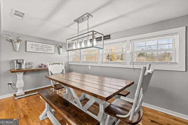a dining room with wooden floor and chandelier