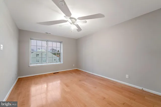 an empty room with windows and fan