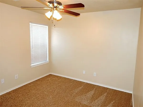 an empty room with a window and a fan