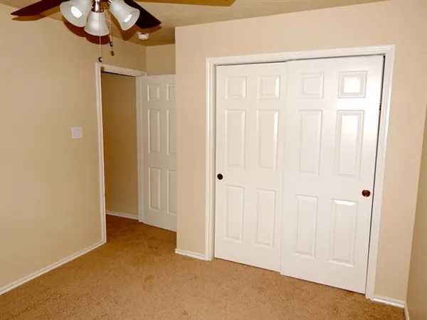 an empty room with a window and a chandelier fan