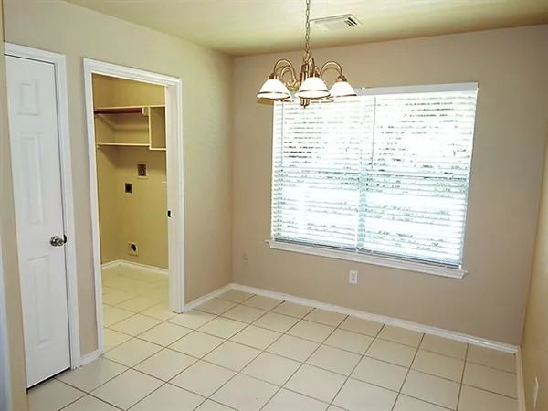 an empty room that has a window and a chandelier