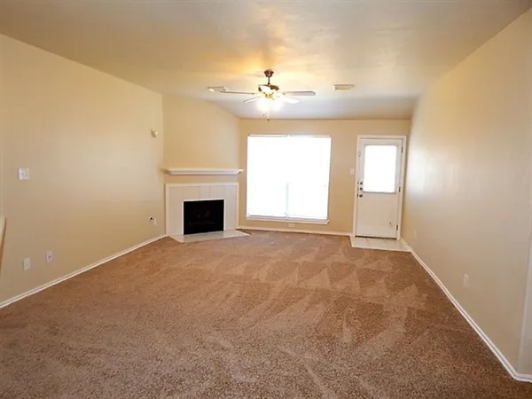 an empty room with windows and fireplace