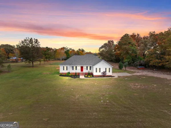 a view of a big house with a big yard and large trees