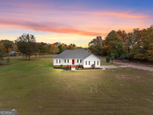 a view of a big house with a big yard and large trees