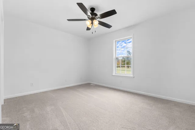 an empty room with ceiling fan and window