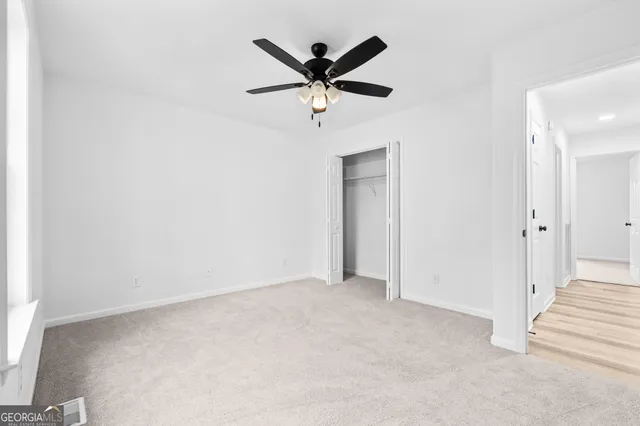 an empty room with closet and ceiling fan
