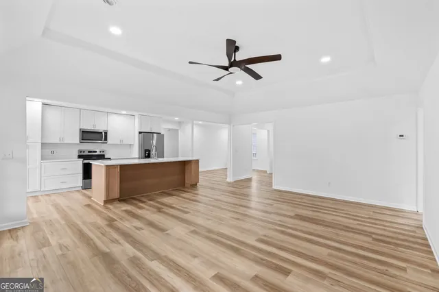 a view of kitchen and empty room with wooden floor