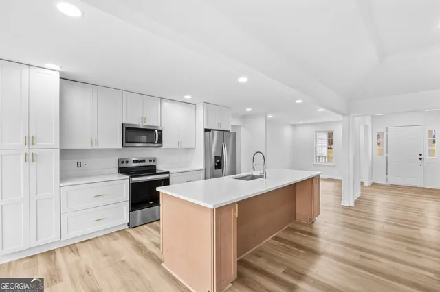 a large kitchen with stainless steel appliances a sink a stove and a refrigerator