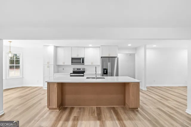 a large white kitchen with wooden floor