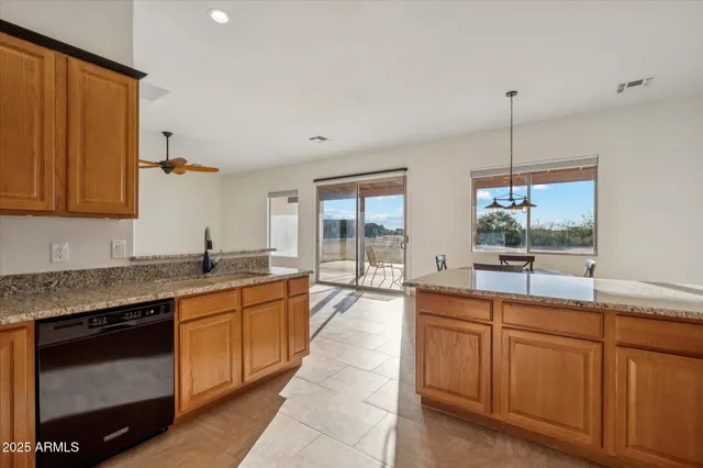 a large kitchen with kitchen island granite countertop a sink a counter space appliances and cabinets