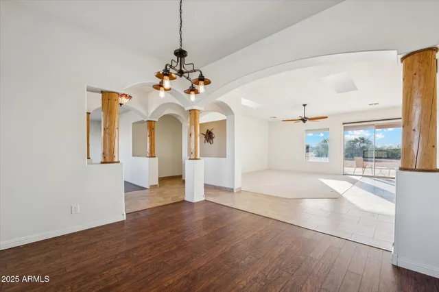a view of a room with wooden floor chandelier and windows