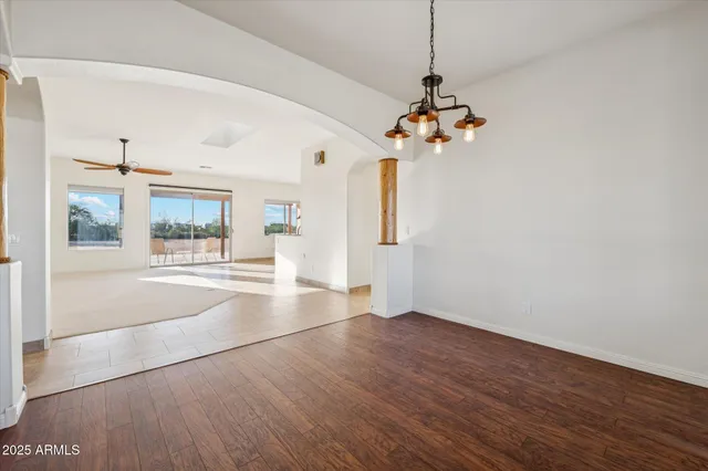 a view of a room with wooden floor chandeliers and kitchen view