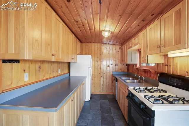 a kitchen with stainless steel appliances granite countertop a stove a refrigerator a sink dishwasher and wooden cabinets with large windows