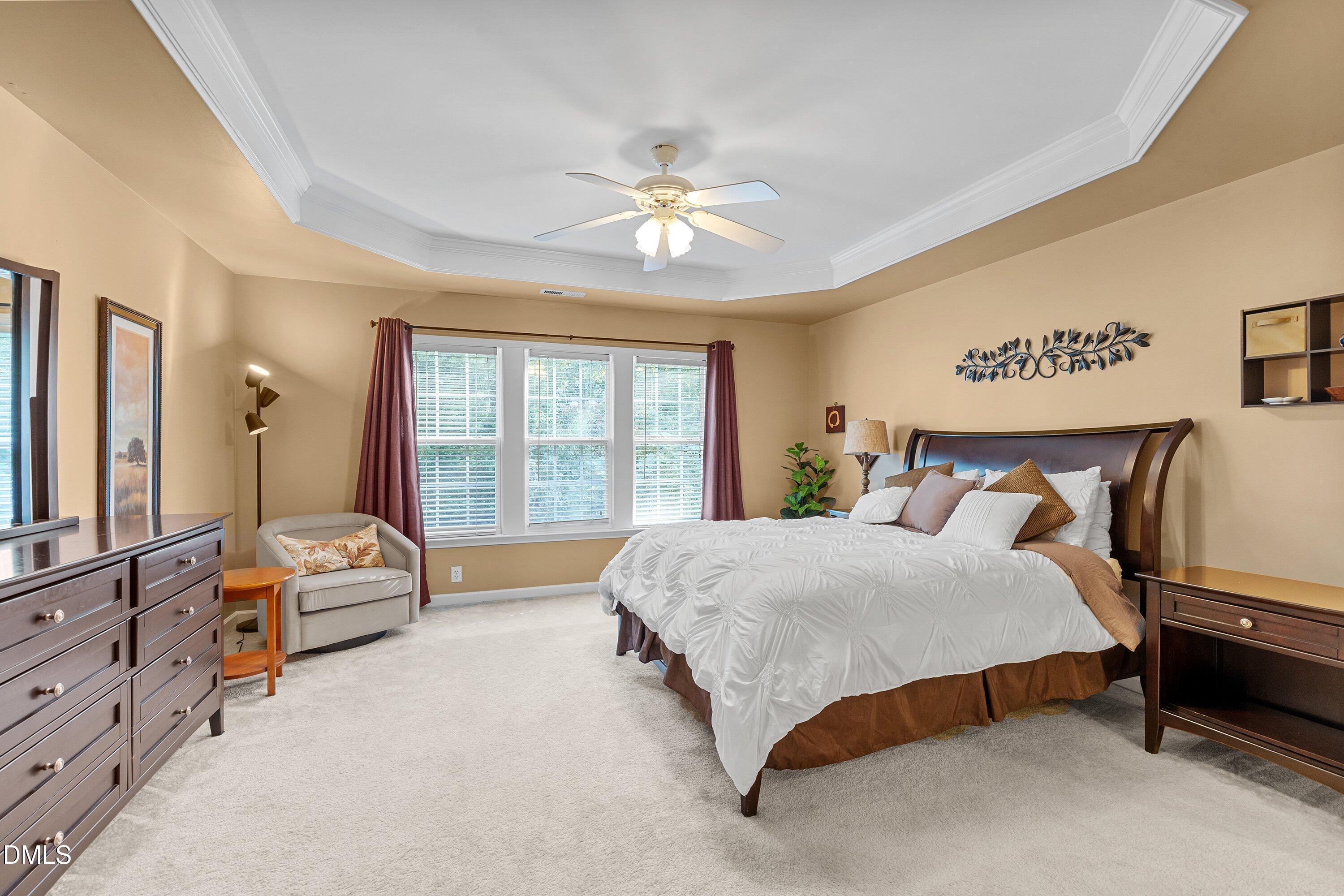 3613 Lion Ridge Court Raleigh, NC 27612 - Photo 25 of 40 a spacious bedroom with a bed a chandelier and a large window