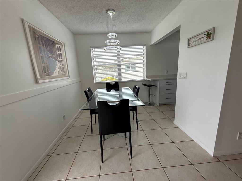 144 Farnham F Deerfield Beach, FL 33442 - Photo 16 of 36 a living room with a black white checkered floor with a dining table and chairs