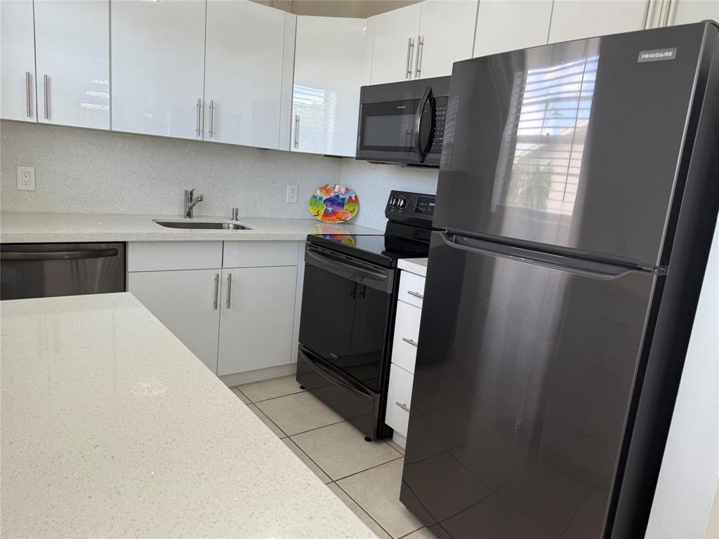 144 Farnham F Deerfield Beach, FL 33442 - Photo 21 of 36 a kitchen with a refrigerator sink and cabinets