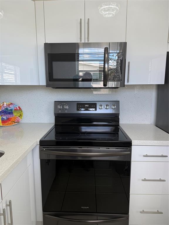 144 Farnham F Deerfield Beach, FL 33442 - Photo 24 of 36 a kitchen with stainless steel appliances granite countertop a stove and a microwave