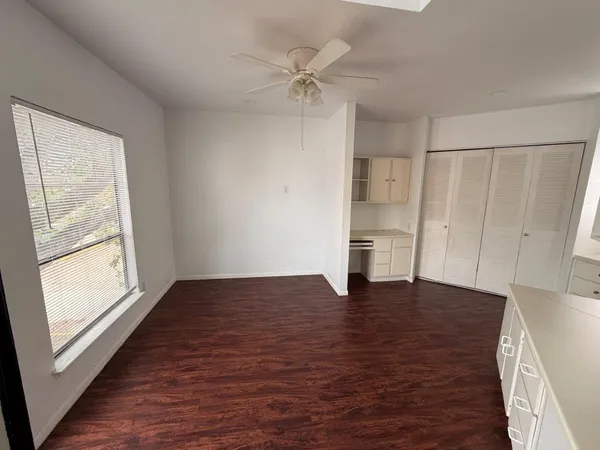 a view of an empty room with a window and wooden floor