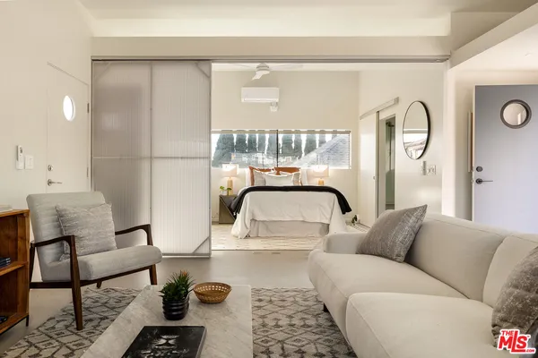 a living room with furniture and a large window with kitchen view