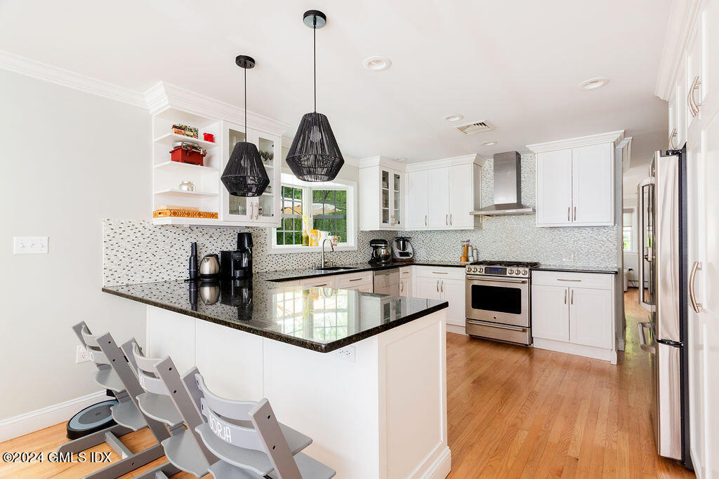 25 Griffith Road Riverside, CT 06878 - Photo 7 of 27 a kitchen with granite countertop stainless steel appliances a stove a sink a center island and wooden floor