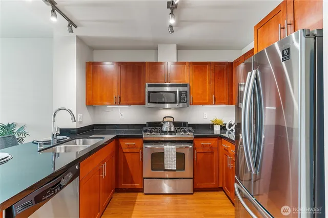 a kitchen with stainless steel appliances granite countertop a stove a sink and a refrigerator
