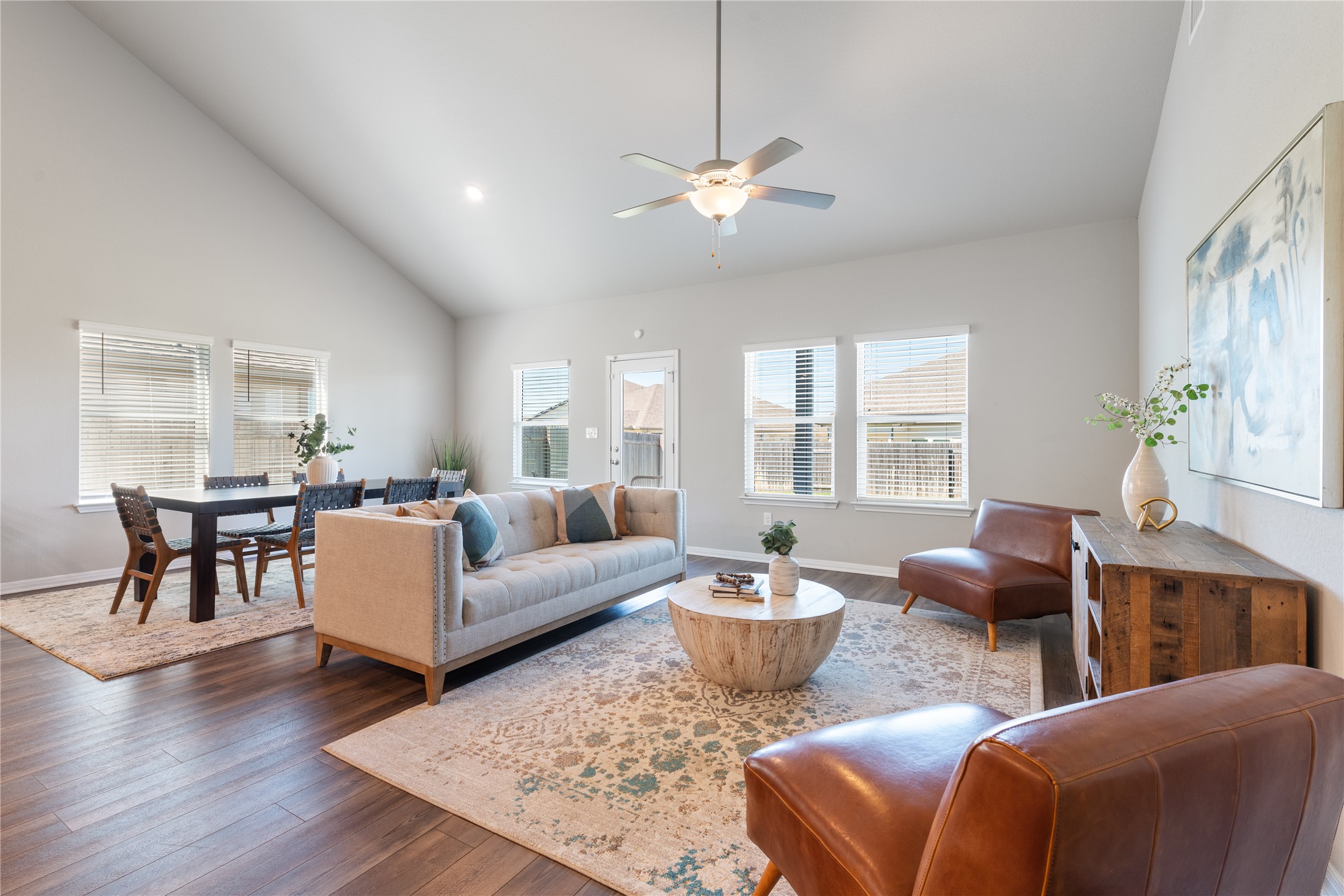 Living area with vaulted ceiling, wood-type flooring, a ceiling fan, and plenty of natural light