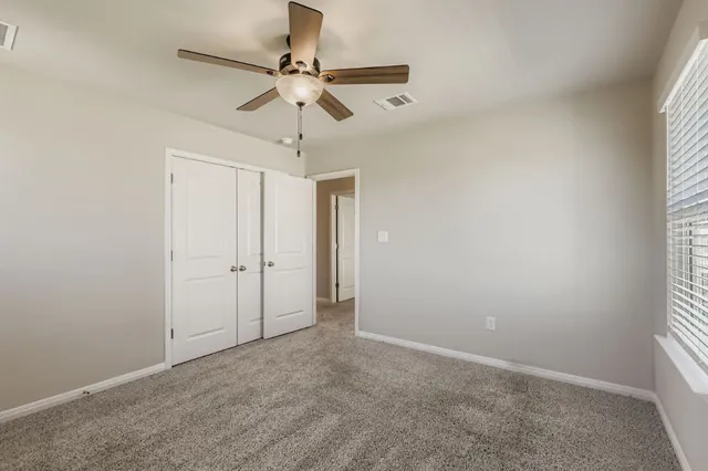 an empty room with a window and a fan