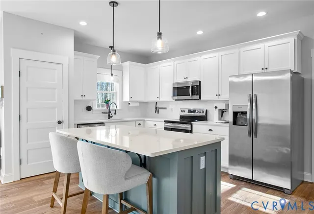 a kitchen with stainless steel appliances granite countertop a sink a stove a refrigerator cabinets and chairs