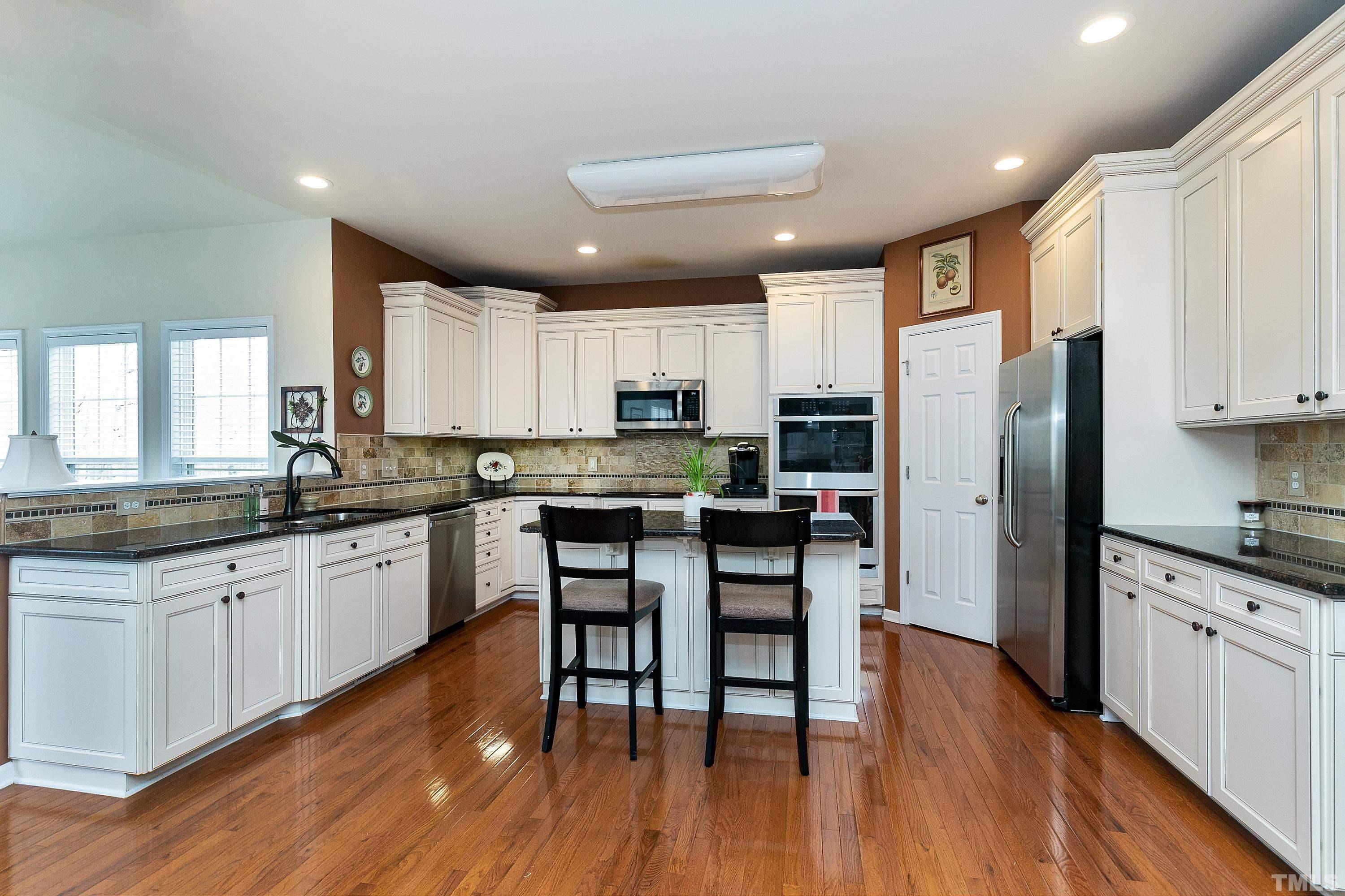 891 Seastone Street Raleigh, NC 27603 - Photo 16 of 51 a kitchen with stainless steel appliances granite countertop wooden floor sink and stove