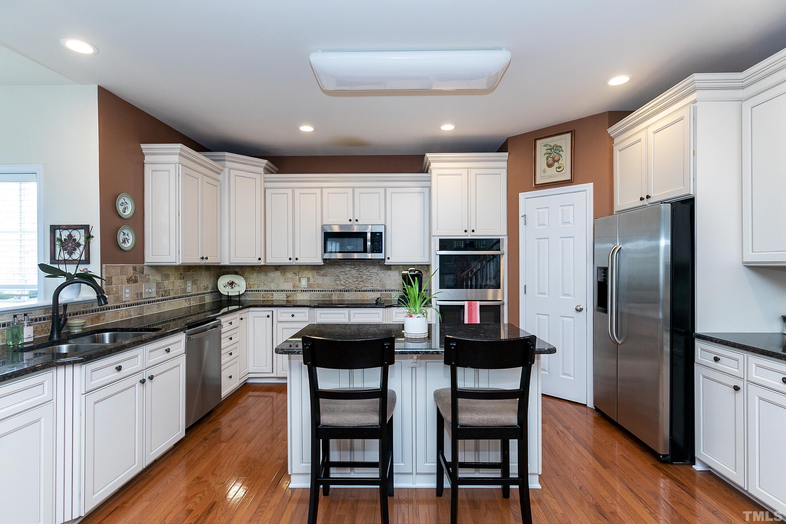 891 Seastone Street Raleigh, NC 27603 - Photo 8 of 51 a kitchen with stainless steel appliances granite countertop a dining table chairs refrigerator and cabinets