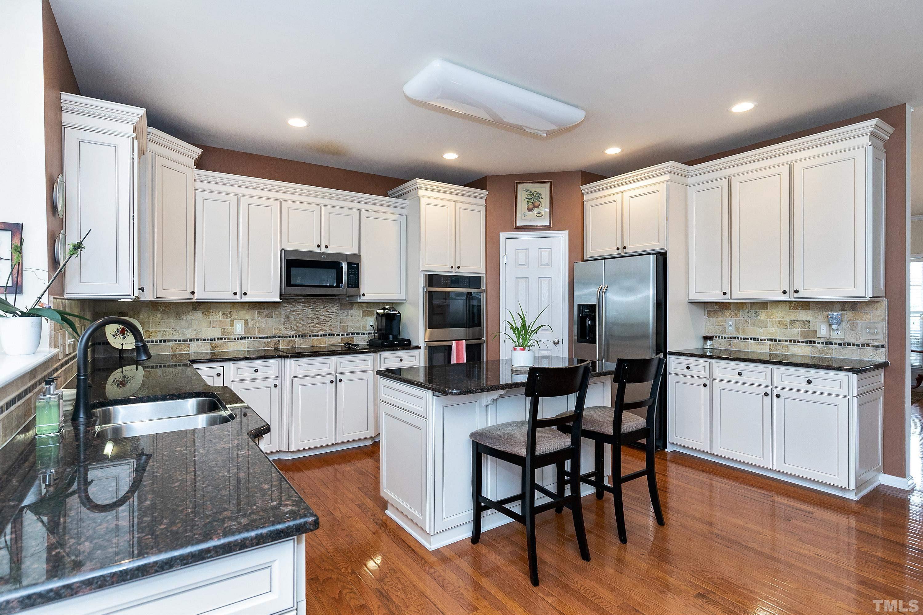 891 Seastone Street Raleigh, NC 27603 - Photo 10 of 51 a kitchen with stainless steel appliances granite countertop a refrigerator a stove top oven a sink a dining table and chairs with wooden floor