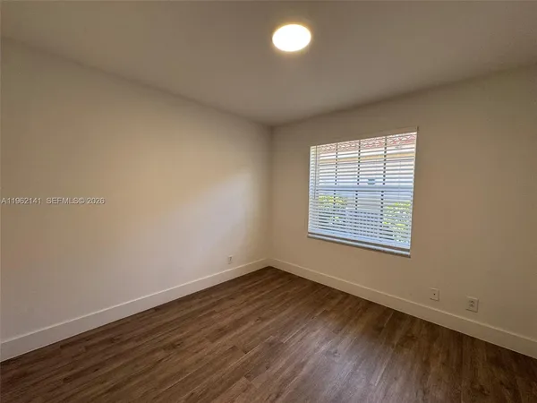an empty room with wooden floor & closet area