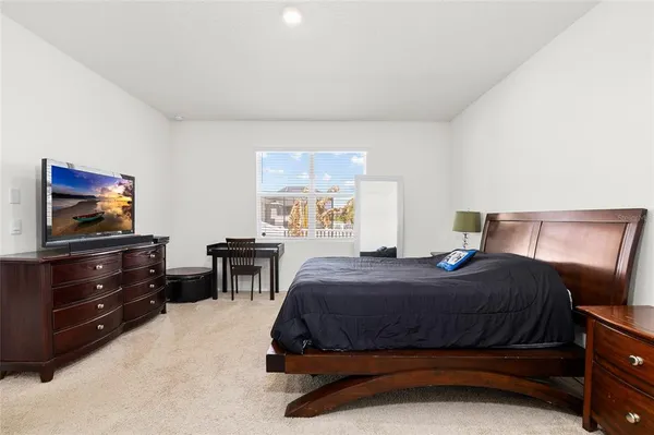 a bedroom with a bed and a flat tv screen on dresser