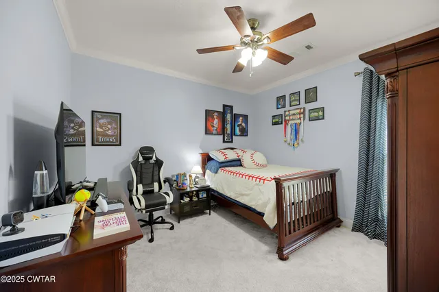 a bedroom with a bed a computer on desk and a dresser