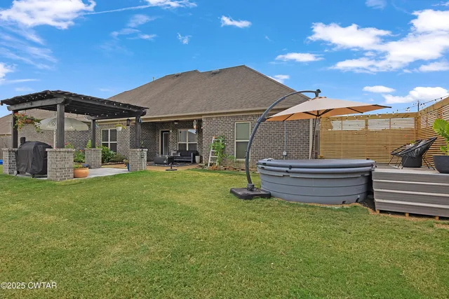 a backyard of a house with wooden table and chairs