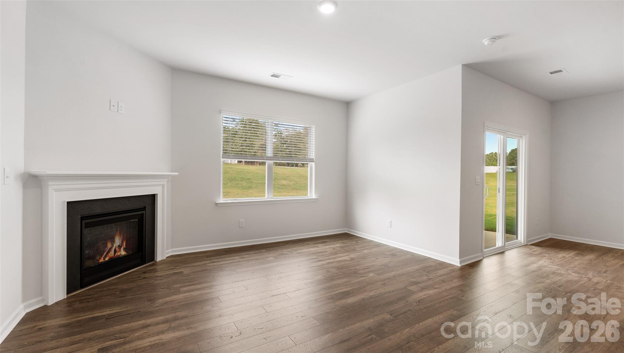 100 Piney Wds Road Fletcher, NC 28732 - Photo 14 of 33 an empty room with wooden floor a fireplace and windows