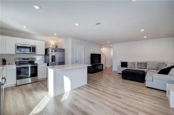 a living room with furniture a flat screen tv and kitchen view