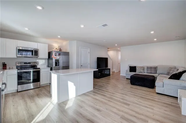 a living room with furniture a flat screen tv and kitchen view