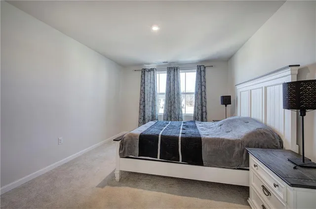 a bed sitting in a spacious bedroom next to a window and dresser