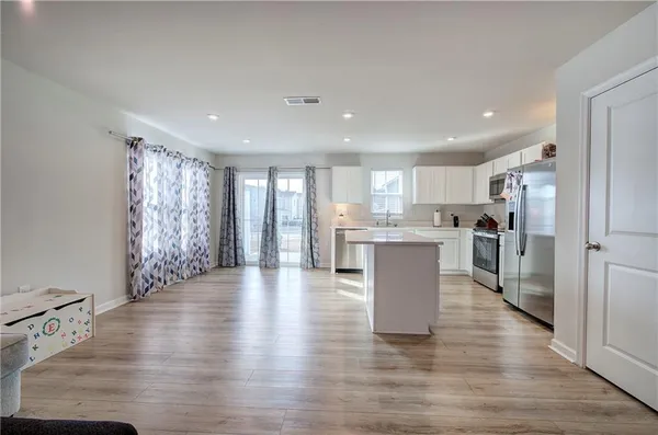 a view of a kitchen with kitchen island wooden floors stainless steel appliances and a window