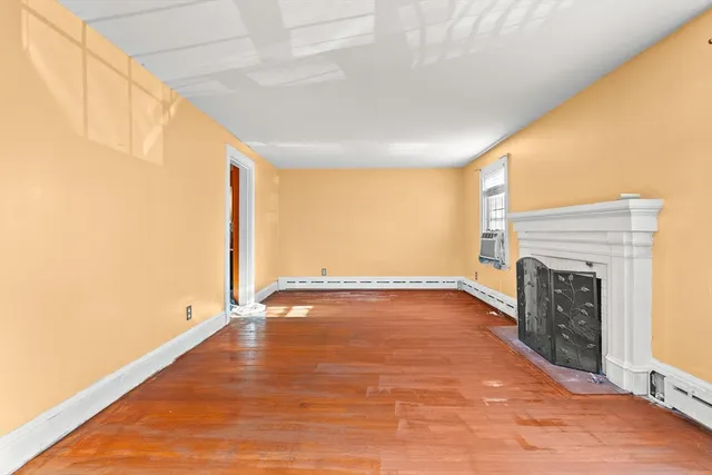 a view of an empty room with a fireplace and a window