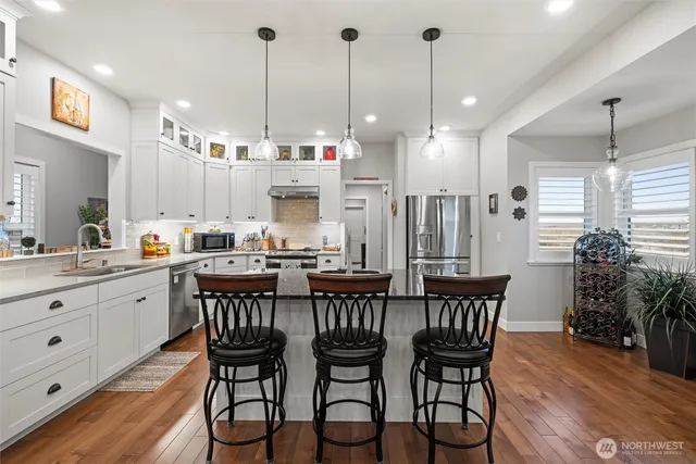a kitchen with stainless steel appliances kitchen island granite countertop a dining table chairs and sink