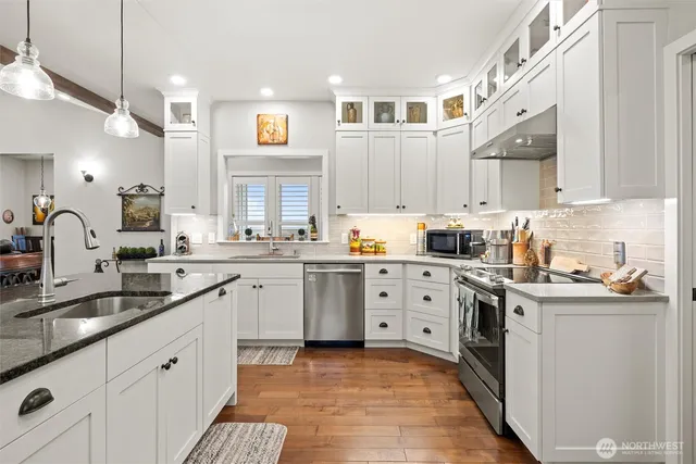 a kitchen with cabinets stainless steel appliances a sink and a window