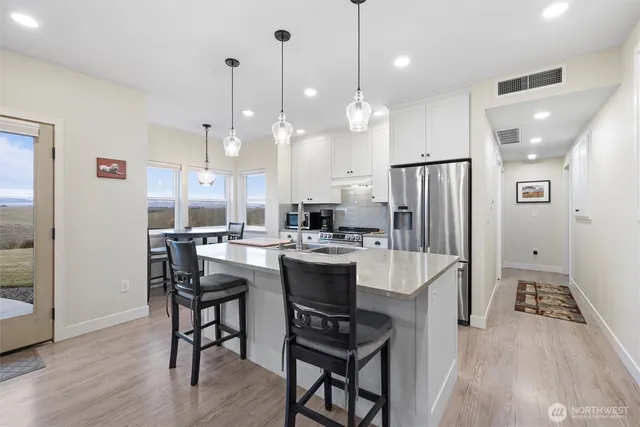 a kitchen with a refrigerator a sink dishwasher a dining table and chairs with wooden floor