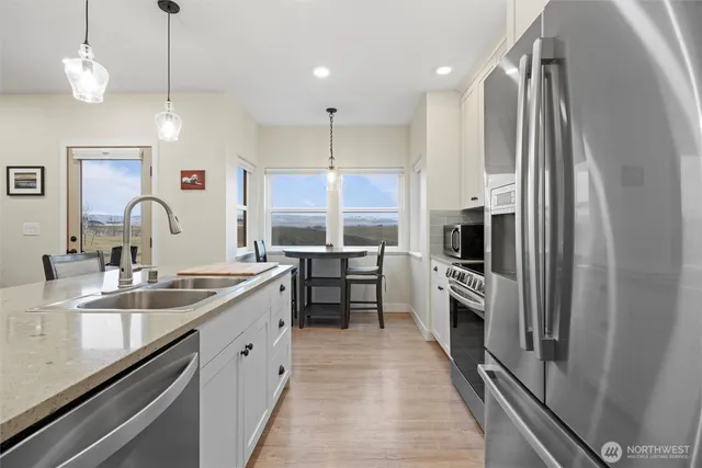 a large kitchen with stainless steel appliances a sink a stove and a refrigerator