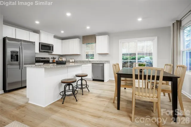 a kitchen with stainless steel appliances kitchen island granite countertop a table chairs microwave and view living room